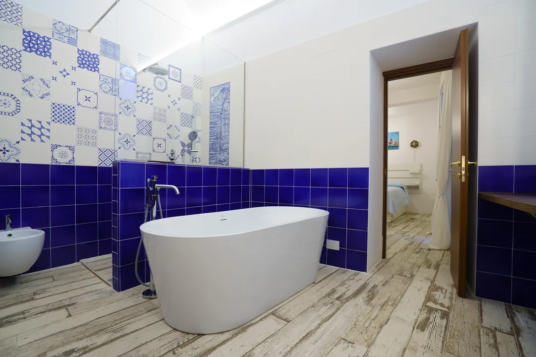 Bagno con vasca freestanding e maioliche bianche e blu